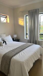 a bedroom with a large white bed with windows at Jackal Creek Golf Estate in Roodepoort