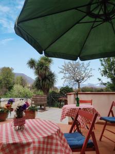 um pátio com uma mesa e um guarda-chuva verde em Casa Fasano Amalfi Coast em Vietri