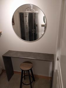 einen Spiegel an einer Wand über einer Theke mit einem Stuhl in der Unterkunft La Petite Maison à Vieillecour in Saint-Pierre-de-Frugie