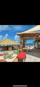 two pictures of a beach with a bench and umbrellas at La Tanière de Saint-Martin in Orient Bay
