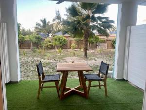 a table and two chairs on a patio with a palm tree at La Tanière de Saint-Martin in Orient Bay