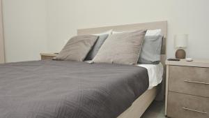 een slaapkamer met een bed met kussens en een nachtkastje bij Widnet il-Bahar in Marsalforn
