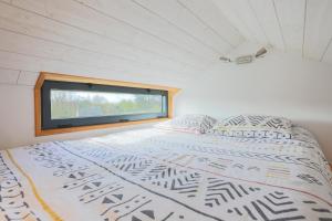 ein großes Bett in einem Zimmer mit Fenster in der Unterkunft Très Jolie Tiny House Tout Confort in Prat