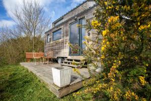 a tiny house sitting on a wooden deck at Très Jolie Tiny House Tout Confort in Prat