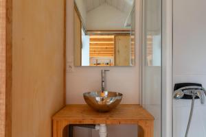 Très Jolie Tiny House Tout Confort في Prat: وعاء فوق طاولة خشبية في الحمام