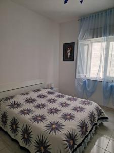 1 dormitorio con 1 cama con colcha de flores y ventana en Agriturismo Fuoco D'Amalfi Villa Iazzetta, en Amalfi