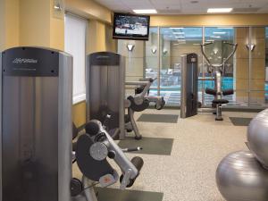 einen Fitnessraum mit mehreren Trainingsgeräten und einem TV in der Unterkunft Homewood Suites By Hilton Downers Grove Chicago, Il in Downers Grove
