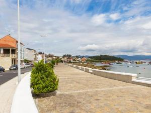 a walkway next to a river with boats in the water at Apartamentos Illa de Arousa Centro 3000 in Isla de Arosa