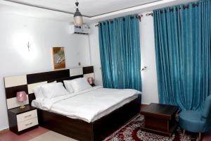 una camera da letto con un letto con tende blu e una sedia blu di FANZMA ApArtment a Aso