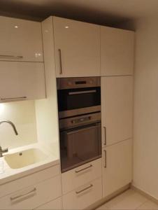 eine Küche mit weißen Schränken, einem Backofen und einer Spüle in der Unterkunft Spacious modern 3 bedroom aparment in Prag