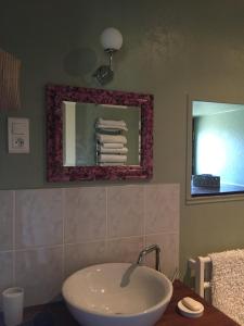 La salle de bains est pourvue d'un lavabo et d'un miroir. dans l'établissement Gîte Maison Maitri, à Forgès