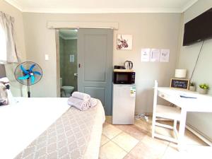 a small kitchen with a white refrigerator and a desk at OR Tambo Stay Unit 3 in Boksburg +8 photos