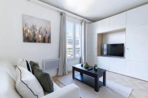 ein Wohnzimmer mit einem Sofa, einem TV und einem Tisch in der Unterkunft So Ouest/Courcelles : Magnifique Studio in Levallois-Perret