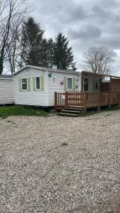 a large white mobile home with a wooden porch at Mobil home climatisé Proche Europa Park in Boofzheim