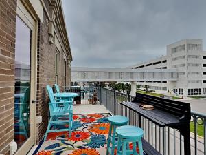 uma varanda com bancos azuis, uma mesa e cadeiras em Stables On The Strand em Galveston