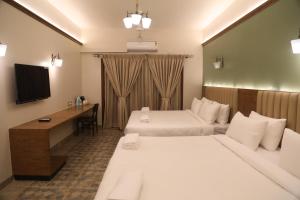 Habitación de hotel con 2 camas y escritorio en Summer House Nandi Foothills, en Nandi