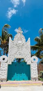 una puerta blanca y azul con palmeras en el fondo en Mayan Mittoz en Holbox Island
