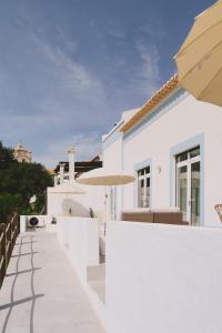 a white house with a patio and an umbrella at Pure Flor de Esteva in Vila do Bispo