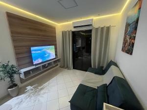 a living room with a couch and a flat screen tv at Apartamento Canto Do Forte - Praia Grande Top in Praia Grande