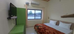una camera con letto, TV e finestra di Shivansh Palace HomeStay & Marriage Garden a Khajurāho