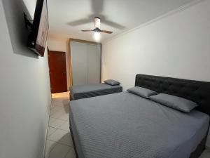 um quarto com uma cama e uma ventoinha de tecto em Apartamento Canto Do Forte - Praia Grande Top na Praia Grande
