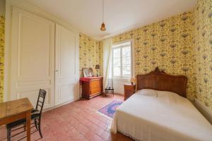 um quarto com uma cama, uma secretária e uma janela em Château Monvallon em Charentay