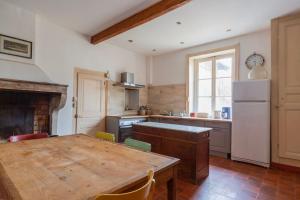 uma cozinha com uma mesa de madeira e uma cozinha com uma lareira em Château Monvallon em Charentay
