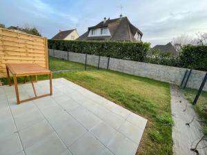 a wooden bench sitting on a patio in a yard at Freesia YourHostHelper in Caen