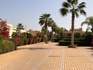 LUXUEUSE VILLA AVEC PISCINE PRIVEE PROCHE D'AGADIR في أغادير: ممشى من الطوب مع النخيل في منتجع