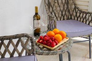 Magnificent Riviera Residence في أثينا: طاولة مع صحن من الفواكه وزجاجة من النبيذ