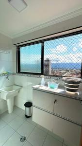 a white bathroom with a sink and a window at Apto Lindo e Completo Beira Mar - Vila Caiçara in Solemar