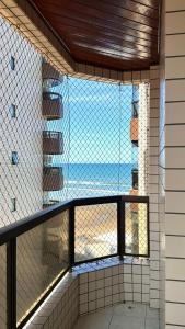 a view of the beach from a balcony with a window at Apto Lindo e Completo Beira Mar - Vila Caiçara in Solemar