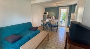 a living room with a blue couch and a table at Maisonnette 6 personnes à 500 m de la plage Parking 6GOEL18 in Le Barcarès