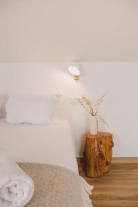 a bedroom with a bed and a plant on a wooden stump at Pure Flor de Esteva in Vila do Bispo