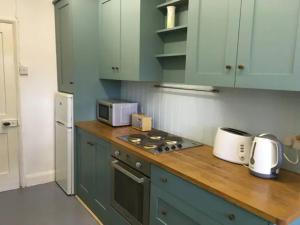 a kitchen with green cabinets and a counter top with a microwave at Cosy Family Cottage, Semi Rural Retreat - Dogs Welcome! Nearby Countryside, Beaches & Goodwood in Eartham
