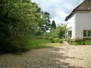 a house with a gravel driveway next to a yard at Cosy Family Cottage, Semi Rural Retreat - Dogs Welcome! Nearby Countryside, Beaches & Goodwood in Eartham