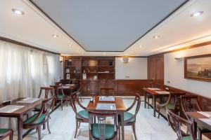 Un comedor con mesas y sillas de madera. en Soho Boutique Los Naranjos, en Málaga