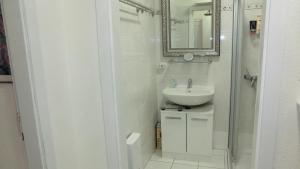 a white bathroom with a sink and a mirror at Wohnung an der Lagune in Büsum