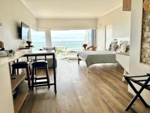 a bedroom with a bed and a desk and a table at Small Bay Beach Suites in Cape Town