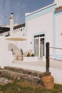 a white house with a patio and an umbrella at Pure Flor de Esteva in Vila do Bispo