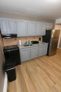 cocina con armarios blancos, fregadero y nevera en 2-Bed Stylish Space mins to NYC, en Jersey City