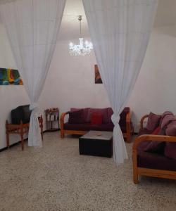 una sala de estar con 2 sofás y una lámpara de araña. en L'espadon de Mahdia Maison avec petit jardin en Mahdia