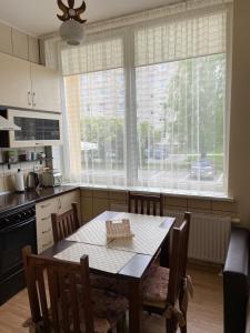 a kitchen with a table and chairs and a large window at Butų nuoma Šilutėje in Šilutė
