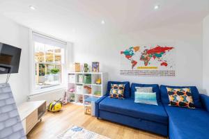 a living room with a blue couch and a map on the wall at The Lymington Hub Slps 13 hot tub/chef/spa in Lymington