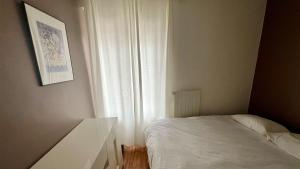 sypialnia z białym łóżkiem i oknem w obiekcie Appartement en centre-ville w Genewie