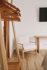 a living room with a white chair and a tv at Pure Flor de Esteva in Vila do Bispo