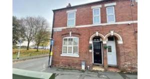 a red brick building with a white door on a street at Contractors Grove 2 Bed House Town Centre Location in Wellingborough