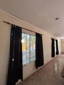 2 ventanas con cortinas negras en una habitación en Casa de Campo en San Pedro