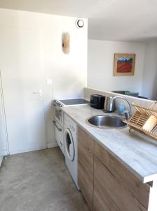 een keuken met een wastafel en een wasmachine bij Duplex dans résidence avec Piscine à Uzès in Uzès