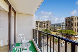 a balcony with two chairs and a view of a city at Waikiki Banyan 913 in Honolulu